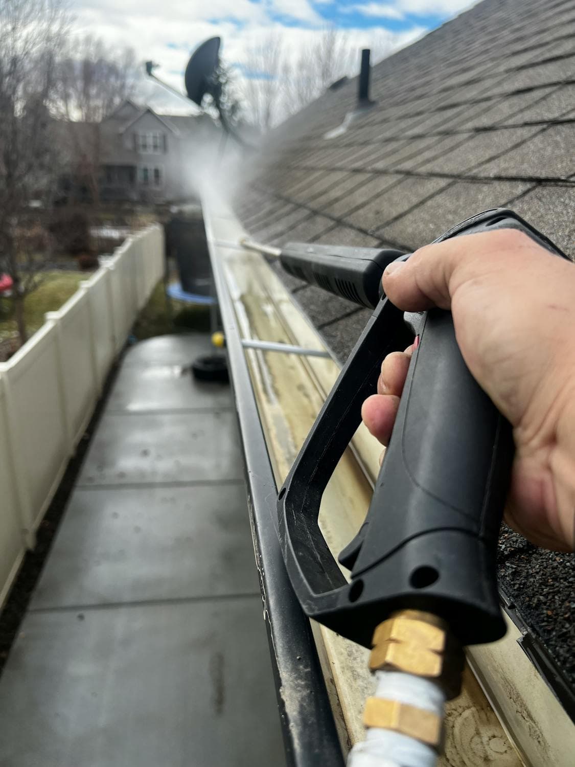 Gutter cleaning with pressure washer on residential roof